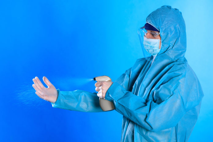 Cleaning And Disinfection A Medical Man In A Medical Protective Full Protected Suit , A Means Of Protection Against The Virus, Uses A Spray To Disinfect . Epidemia Coronavirus. Covid 19