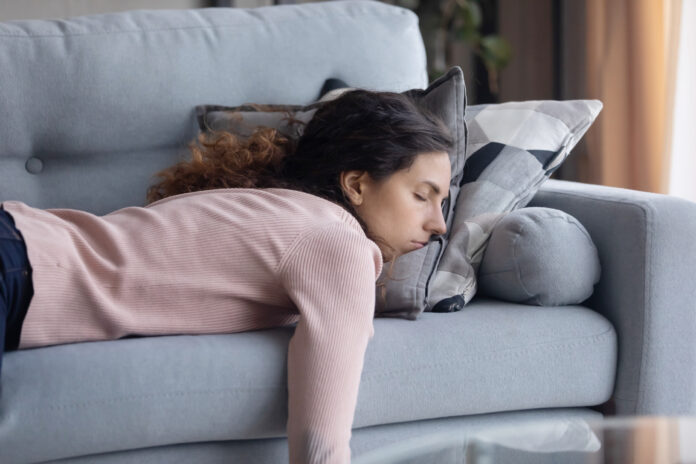 Tired Young Woman Sleeping On Couch At Home